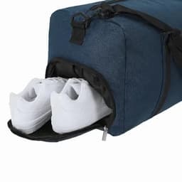 A gym bag in navy blue with a zippered compartment containing white sneakers. Features a shoulder strap and handle.