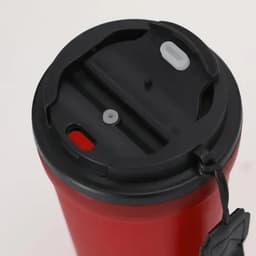 A drink bottle with a red body and a black lid featuring multiple openings and a strap for easy carrying.