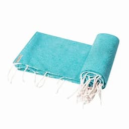 A rolled-up turquoise beach towel with white fringes, featuring a small logo tag.