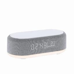 A grey oval clock radio with a fabric exterior displaying a digital time readout.