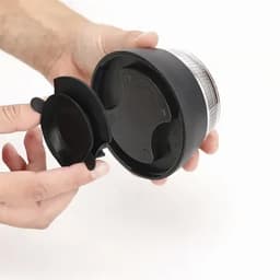 A drink bottle in black with a transparent top, being held while its cap is being removed. Features a logo on the side.