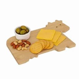 A wooden serving board shaped like a cow, featuring cheese slices, crackers, nuts, and green olives.