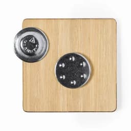 A square bamboo coaster with a metal disc attached, featuring a silver finish and circular indentations.