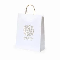 A white paper bag with a decorative logo and handles, featuring a floral design in gold.
