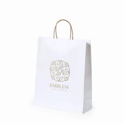 A white paper bag with a decorative design and a logo, featuring brown handles.