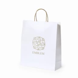 A white shopping bag with a decorative gold logo and handles.