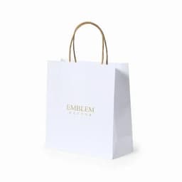 A white paper bag with a gold logo and two brown handles.