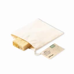 A bar of solid soap in a natural cotton bag, featuring a decorative edge and an earthy colour palette.