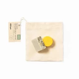 A solid shampoo soap in yellow and white, with a natural texture, packaged in a small fabric bag.