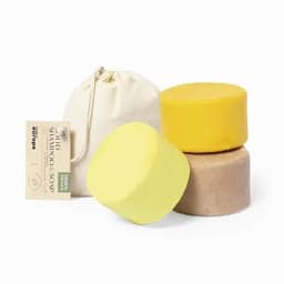 A set of solid shampoo soaps in yellow and brown, accompanied by a drawstring bag, featuring a brand logo.