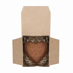 A heart-shaped product in a cardboard box filled with shredded paper. The box is open, revealing the heart inside.