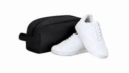 A black toiletry bag next to a pair of white sneakers with a textured design on the side.
