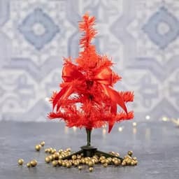 A decorative orange Christmas tree with a red bow sits on a surface surrounded by golden beads.