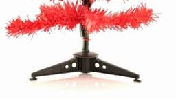 A red artificial Christmas tree with a black plastic stand, showcasing shiny tinsel branches.