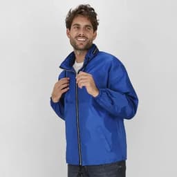 A man wearing a blue jacket with a zippered front and a high collar, posed against a neutral background.