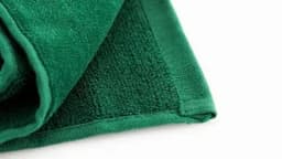 A green golf towel, featuring a textured surface and fold design, with a branding logo displayed.