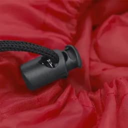 A red sleeping bag with a black toggle for adjusting the opening, featuring a textured fabric.