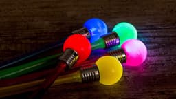 A collection of glowing drink stirrers in red, blue, green, pink, and yellow, with metallic tops.