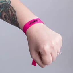 A pink wristband with a logo, worn on a hand featuring a tattoo.