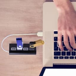 A USB hub featuring multiple ports in black with blue and gold accents, connected to a laptop.
