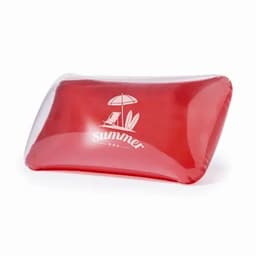 A red inflatable pillow featuring a summer-themed design, including a beach umbrella and chairs. It has a logo on it.