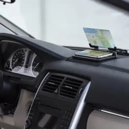 A car dashboard featuring a smartphone and a map displayed on a holder, with black and silver interior elements.