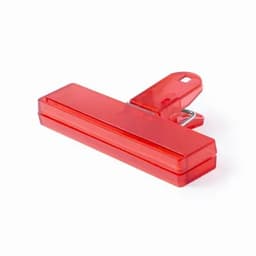 A red clip with a flat rectangular body and a metal spring clip on the back. It features a logo.