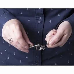 A person holding a silver metal hook with both hands, wearing a navy blue shirt with anchor patterns.