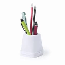 A desk organiser in white holds various pens and pencils, including green, red, and black writing instruments.