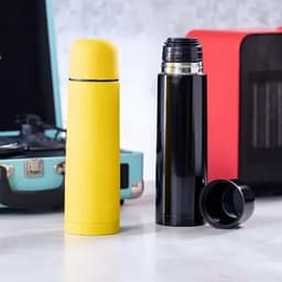 A yellow and black drink bottle set, featuring a glossy finish and a screw-top lid, alongside a portable speaker.