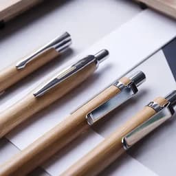 A set of wooden pens with silver accents laid on a geometric patterned surface.
