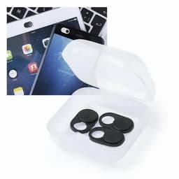 A transparent case containing three black camera lens covers, positioned near a tablet and smartphone.