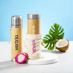 A drink bottle with a bamboo exterior and metal top, accompanied by a fabric carrying pouch and tropical elements.