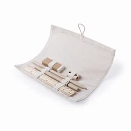A stationery set in a rolled fabric case features wooden pencils, rulers, a sharpener, and a small notebook in neutral colours.