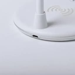 A white wireless charging stand with a circular base featuring a small port on the side.