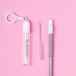 A clear drink bottle with a white cap, a cleaning brush, and a metal straw against a pink background.
