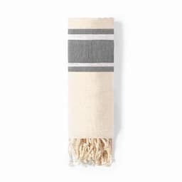 A woven towel in cream and grey, featuring striped patterns and fringed ends. It is neatly rolled.