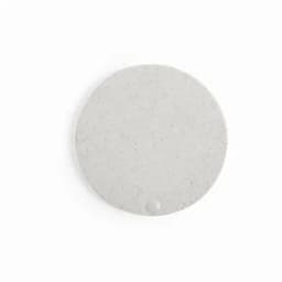 A round, grey coaster with a speckled texture and a small indentation. It has a minimalist design.