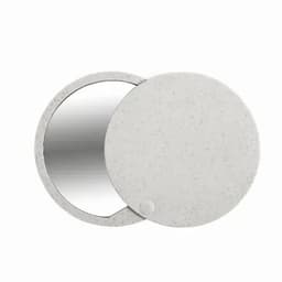 A circular mirror with a textured, light grey casing, featuring a sleek design and a small dot detail.