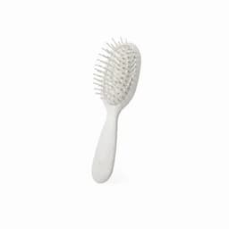 A hairbrush with a white handle and white bristles, featuring a rounded, oval shape and flexible design.