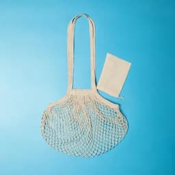 A netted tote bag in a light cream colour, accompanied by a matching fabric pouch.