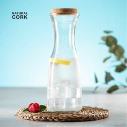 A drink bottle made of glass with a cork lid, featuring lemon slices and ice, on a woven mat with raspberries.
