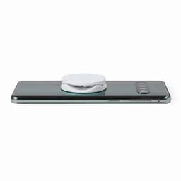 A smartphone with a white circular accessory attached to its back. The device features a sleek, dark design.
