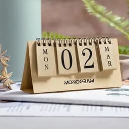 A desk calendar with a wooden base featuring flip cards displaying the day, date, and month. It has a logo on the front.