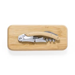 A corkscrew with a wooden handle lies on a bamboo cutting board. The corkscrew has a silver finish.