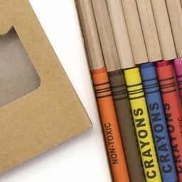 A set of eco-friendly crayons in various colours, packaged in a brown cardboard box with a window.