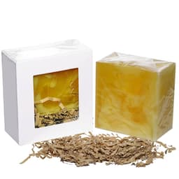 A soap bar in a clear package, yellow in colour, accompanied by shredded paper packing material.