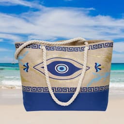 A large beach bag with a blue and beige design, featuring a rope handle and eye motif against a coastal backdrop.