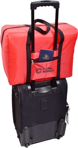 A red insulated bag sits atop a black wheeled suitcase, with a passport visible in the front pocket.