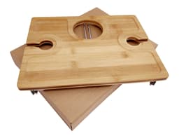 A bamboo picnic board with cutouts for glasses and a central hole, placed on a kraft paper box.